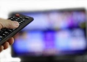 telecomando e schermo - abbuffarsi di guardare il programma televisivo preferito foto