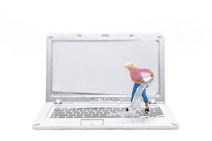 persone in miniatura che puliscono il computer portatile su sfondo bianco foto