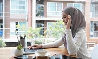 bella bellissima donna musulmana o donna d'affari che ha una riunione online tramite computer portatile nel suo ufficio. foto