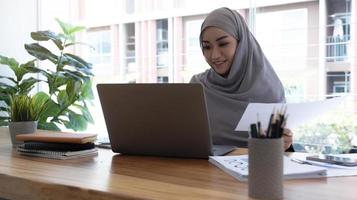 il ritratto di una donna d'affari musulmana che indossa l'hijab lavora su un progetto, fa l'analisi dei documenti. L'imprenditore digitale autorizzato lavora su un progetto di avvio di e-commerce foto