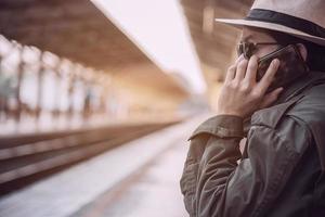 uomo di viaggio in attesa del treno alla piattaforma - attività di stile di vita di vacanza della gente al concetto di trasporto della stazione ferroviaria foto