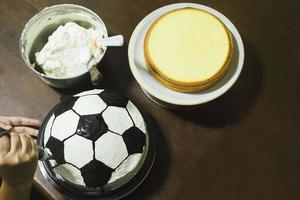 signora che fa la torta, decorazione del modello di calcio foto