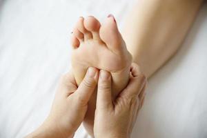 donna che riceve il servizio di massaggio ai piedi dalla massaggiatrice vicino a portata di mano e ai piedi - rilassarsi nel concetto di servizio di terapia di massaggio del piede foto