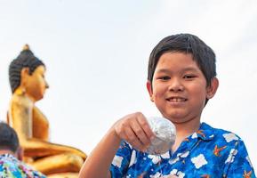 Il ragazzo tailandese partecipa alla vecchia attività tradizionale in un tempio durante il festival di Songkran a chiang mai nel nord della thailandia evento molto famoso della thailandia foto