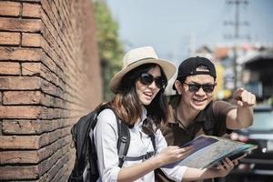 mappa della città della tenuta turistica delle coppie dello zaino asiatico che attraversa la strada - concetto di stile di vita di vacanza della gente di viaggio foto