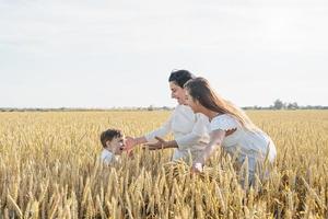 famiglia felice di tre persone, madre e due bambini che camminano sul campo di grano foto