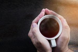 vista dall'alto delle mani dell'uomo che tengono una tazza di caffè calda foto