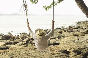 uomo che si rilassa sull'altalena vicino alla spiaggia - rayong della tailandia foto