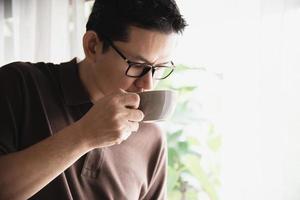 rilassare l'uomo asiatico bere caffè e leggere il libro in una caffetteria in stile moderno - persone con concetto di stile di vita facile tazza di caffè foto
