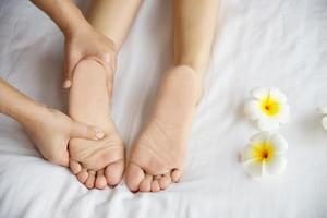 donna che riceve il servizio di massaggio ai piedi dalla massaggiatrice vicino a portata di mano e ai piedi - rilassarsi nel concetto di servizio di terapia di massaggio del piede foto