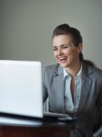 donna sorridente di affari che osserva in computer portatile foto