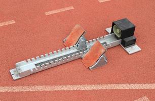 blocchi di partenza di atletica leggera su una pista da corsa rossa in uno stadion foto