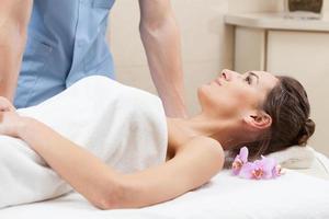 donna avvolta in un asciugamano bianco sdraiato sul lettino da massaggio