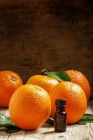olio d'arancia in una bottiglietta e frutta fresca foto