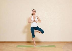donna caucasica sta praticando yoga in studio (vrikshasana) foto