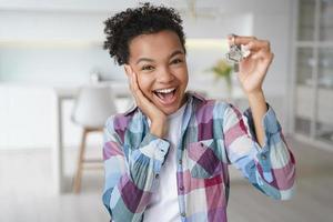 eccitato inquilino adolescente afroamericano che mostra le chiavi della prima nuova casa. servizio di locazione immobiliare foto