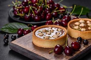 delizioso torrone fresco e crostata di noci con frutti di bosco freschi su un tagliere di legno foto