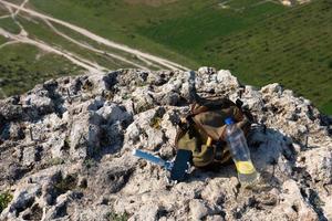 immagine di una bottiglia di plastica e uno zaino turistico su una scogliera di montagna allo stato brado. foto