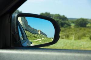 bellissime montagne, roccia bianca, fauna selvatica nello specchietto retrovisore dell'auto. foto