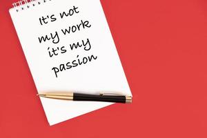 non è il mio lavoro, è la mia passione. testo commerciale, motivazione. scritto su un quaderno bianco con una penna su sfondo rosso. foto