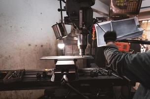 fresatrice che lavora vicino al lavoratore con i guanti. strumento per tagliare il pezzo di metallo. fresatrice verticale con fresa in carburo cementato. industria siderurgica. processo di macinazione. carpenteria metallica. foto