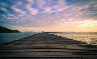 il molo del ponte di legno con un bel cielo all'alba e le nuvole al mattino usano come sfondo naturale. passeggiata turistica sul molo di legno al mare foto