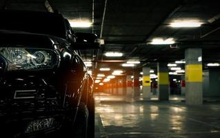 vista frontale dell'auto nera parcheggiata nel parcheggio sotterraneo del centro commerciale. parcheggio del centro commerciale la sera. macchina parcheggiata solitaria di notte. ladro d'auto al concetto di centro commerciale. foto