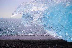 Diamond Beach in Islanda con iceberg blu che si sciolgono sulla sabbia nera e ghiaccio che brilla di luce solare foto