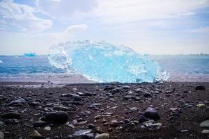 Diamond Beach in Islanda con iceberg blu che si sciolgono sulla sabbia nera e ghiaccio che brilla di luce solare foto