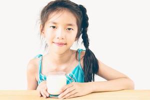 foto in stile vintage di una ragazza asiatica sta bevendo un bicchiere di latte su sfondo bianco