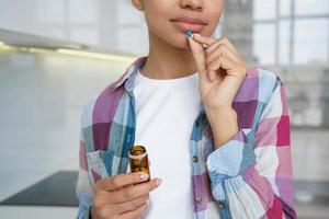 primo piano giovane ragazza in possesso di pillole, assunzione di vitamine, integratore alimentare per la salute dei capelli della pelle della donna foto