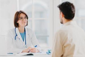 assistenza sanitaria, sessione di terapia e concetto di assistenza. la dottoressa professionista parla con un paziente maschio, fornisce consulenza e fa prescrizioni, scopre i sintomi della malattia, fornisce aiuto. foto