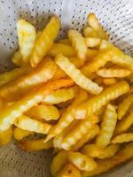 le patatine fritte dorate nello scolapasta di metallo dopo la cottura. foto