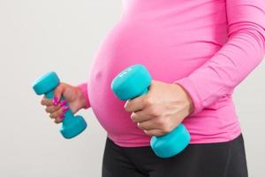 donna incinta che si esercita con i pesi di allenamento foto