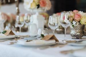 bella tavola servita con cristalleria e coltelleria, decorata con fiori, preparata per l'evento festivo. occasione speciale celebrata in un ristorante o bar di lusso. concetto di impostazione della tabella. tavola nuziale foto