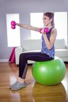 manubri di sollevamento della donna adatta sulla palla di esercizio