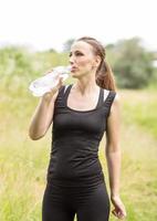 la giovane donna beve l'acqua dopo aver fatto esercizi sportivi foto