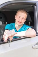 autista. ragazzo teenager caucasico che mostra la patente di guida, chiave dell'automobile. foto