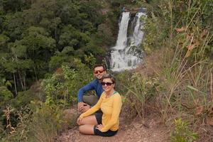 Coppia seduta con vista sulla cascata Veu de noiva lungo il sentiero in indaia vicino a Formosa, Goias, Brasile foto