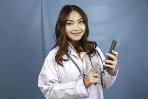 il medico della giovane donna asiatica sta indicando e mostrando lo schermo verde o lo spazio della copia sul suo smartphone foto