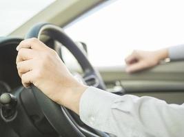 primo piano di un uomo che guida l'auto con una mano, comportamento pericoloso foto