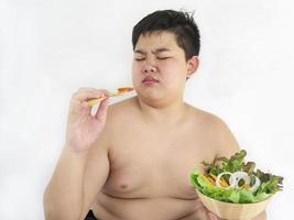 un ragazzo grasso odia mangiare l'insalata di verdure foto