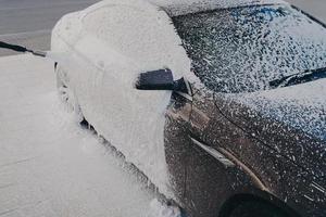 lavare l'auto con una pistola a schiuma ad alta pressione all'aperto foto