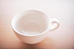 una vecchia tazza da tè bianca veniva posta sul tavolo al mattino con luci e ombre. foto