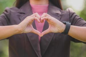 una faccina sorridente donna asiatica che fa il segno della mano del cuore con sentimento d'amore foto