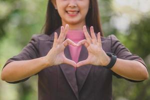 una faccina sorridente donna asiatica che fa il segno della mano del cuore con sentimento d'amore foto