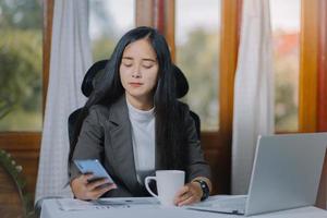 donna asiatica stanca mentre lavora al computer portatile nel suo ufficio. foto