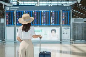 maniglia del bagaglio della holding della mano della giovane donna prima di controllare l'orario di volo in aeroporto, trasporti, assicurazione, viaggi e concetti di vacanza foto