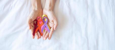 giornata mondiale contro il cancro. nastri colorati di sensibilizzazione di colore rosso, arancione, viola, rosa e giallo per sostenere le persone che vivono e le malattie. concetto di assistenza sanitaria e medica foto