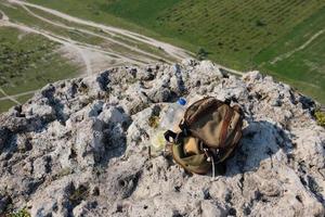 immagine di una bottiglia di plastica e uno zaino turistico su una scogliera di montagna allo stato brado. foto